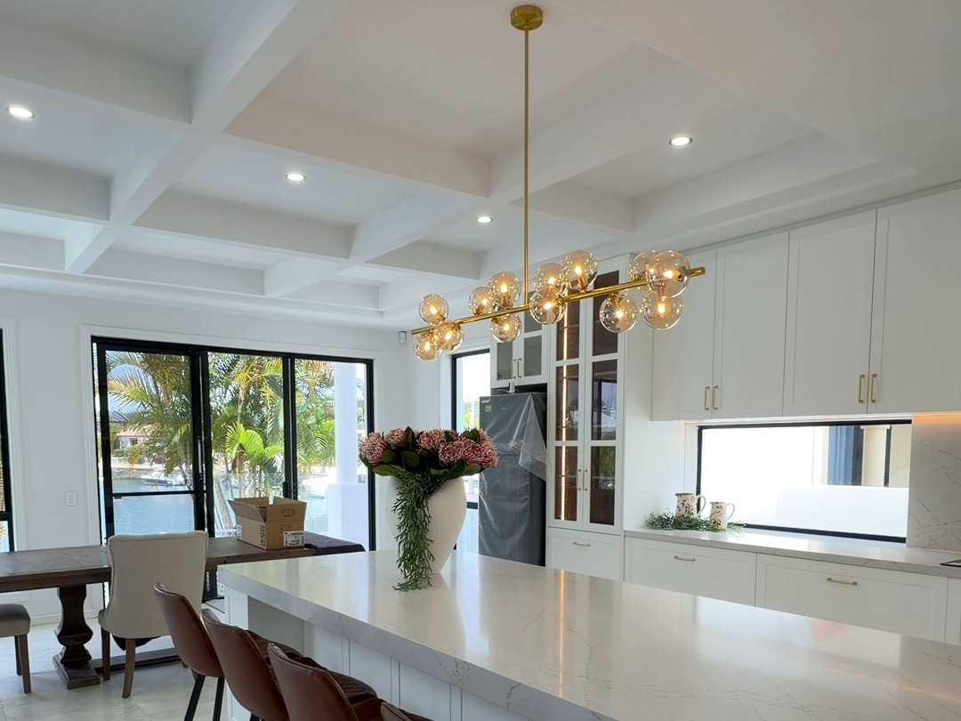 Kitchen with marble island, gold pendant lighting and coffered ceiling