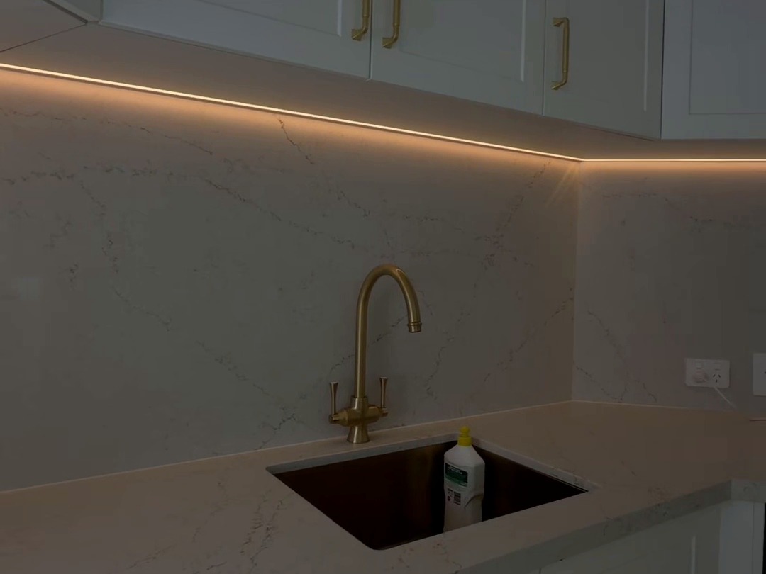 Kitchen sink with warm under-cabinet LED strip lighting